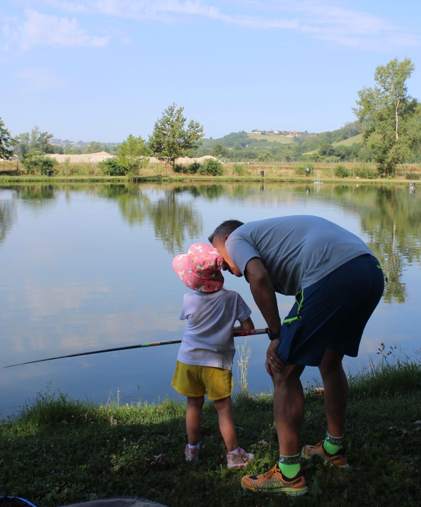 bambina che pesca con l'aiuto di un adulto