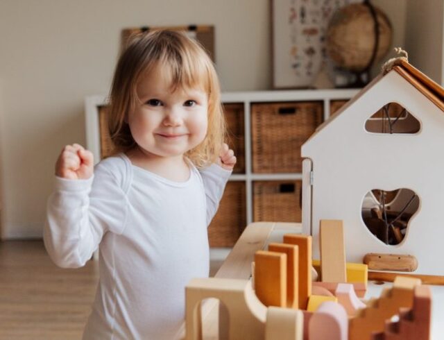 bambina che gioca con casetta e giochi di legno