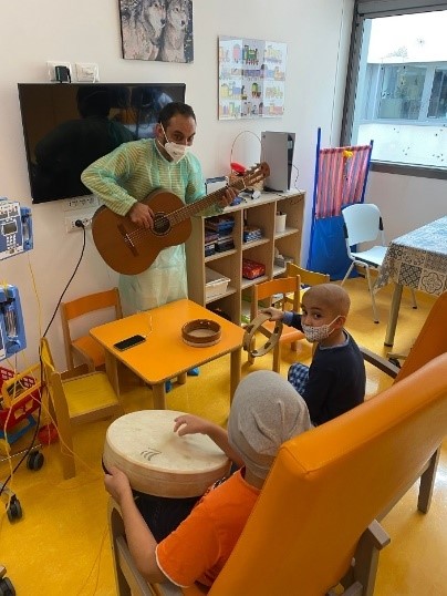 uomo con ragazzi che suonano degli strumenti durante una sessione di musicoterapia in reparto