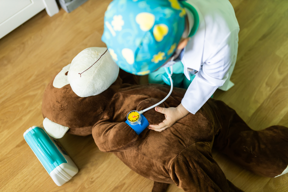 bambino che gioca al dottore con un peluche a forma di scimmia
